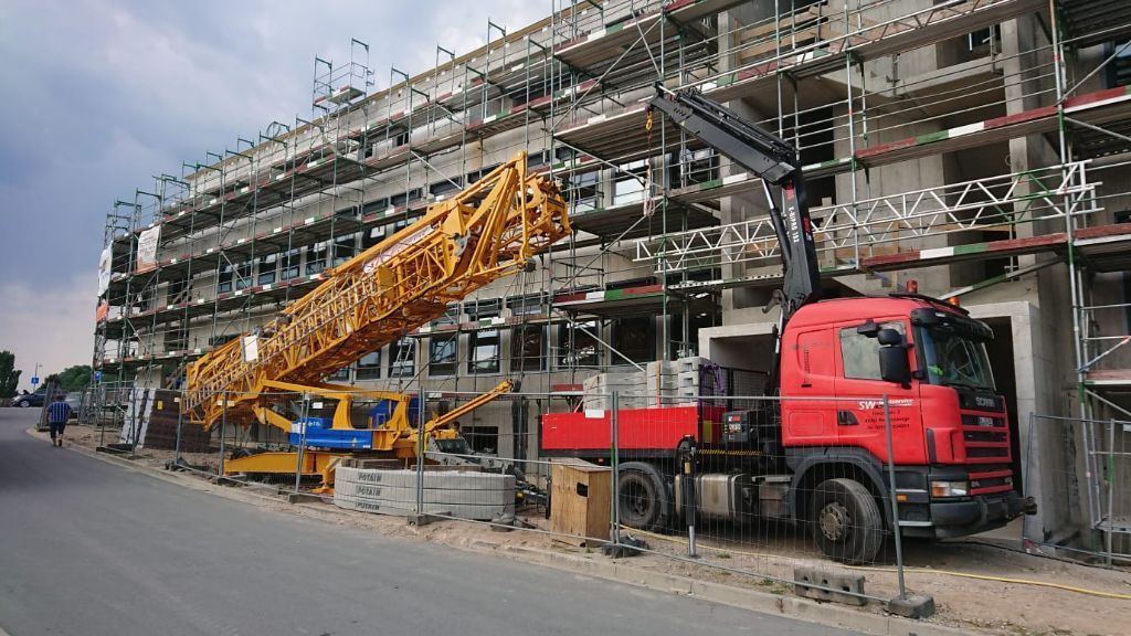 Ein roter Lastwagen steht vor einem im Bau befindlichen Gebäude.