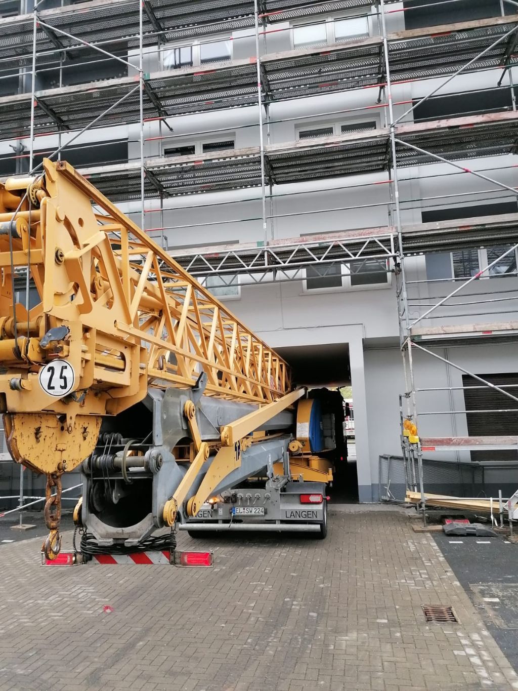 Ein großer gelber Kran steht vor einem im Bau befindlichen Gebäude.