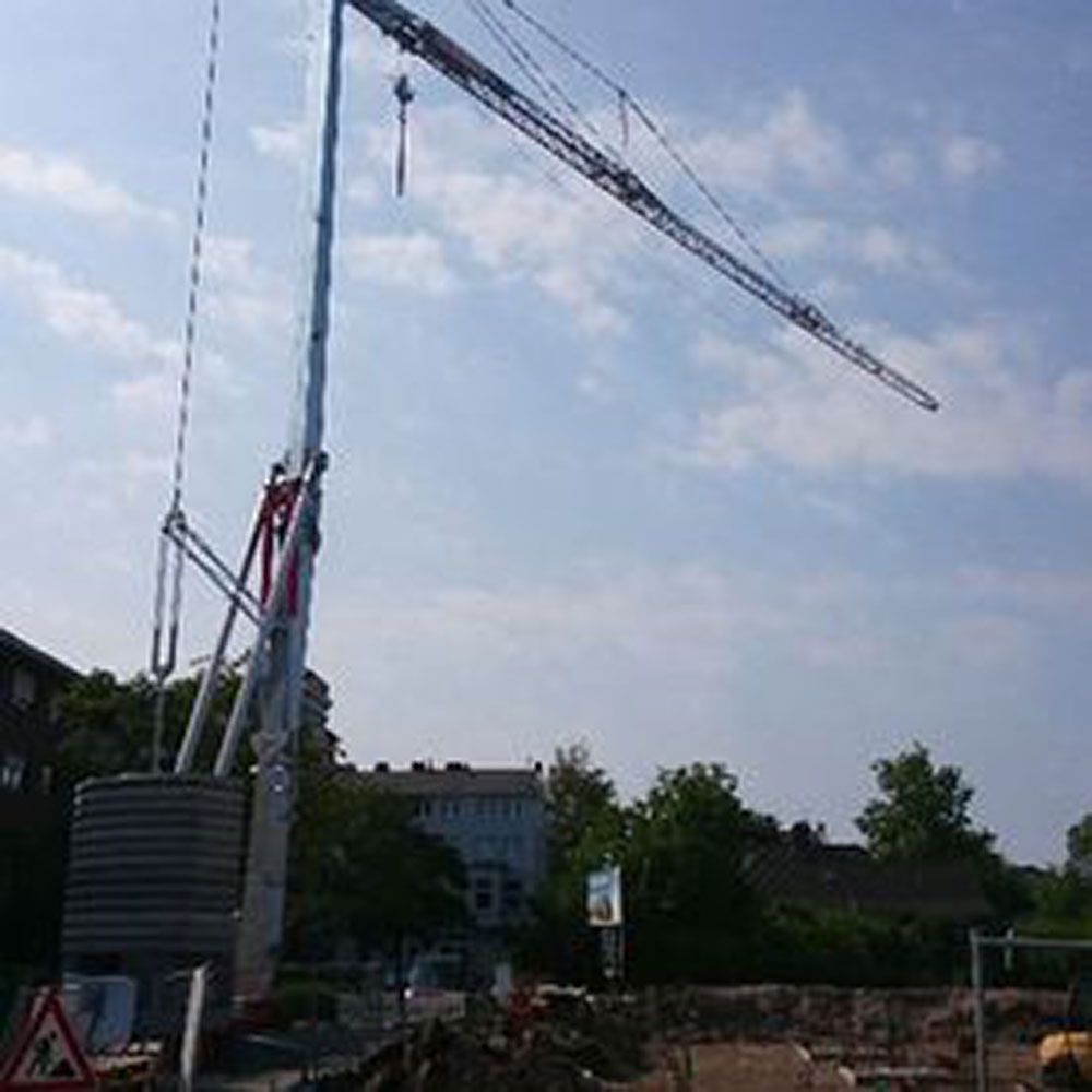 Auf einer Baustelle steht ein großer Kran auf einem Erdhaufen.