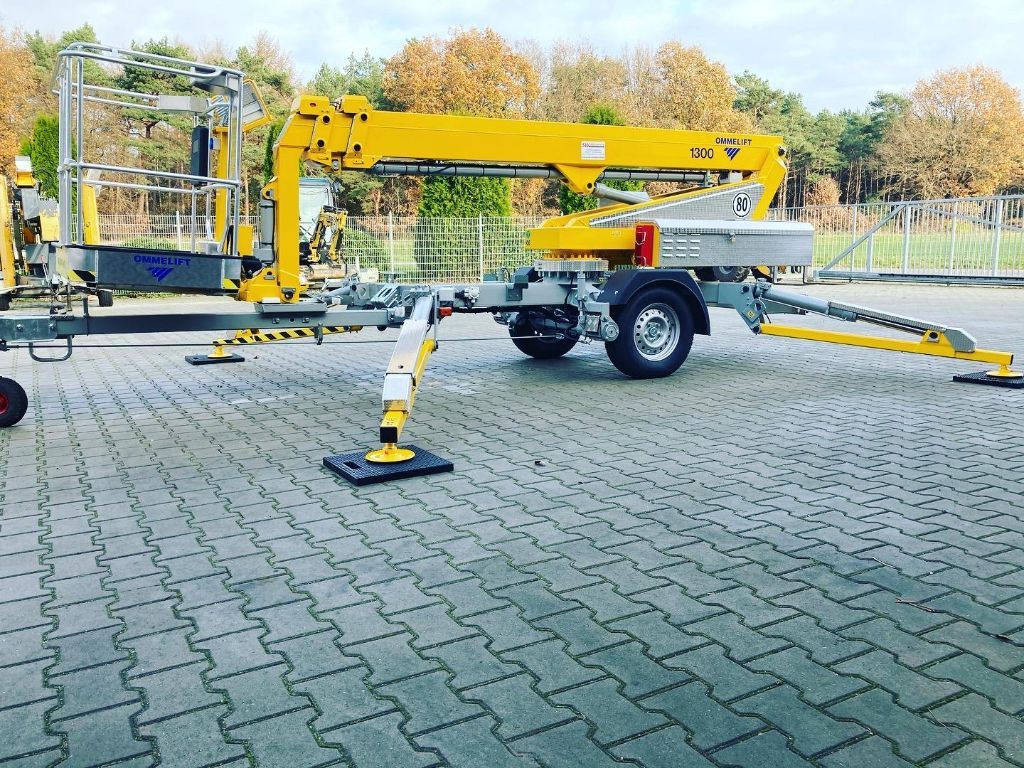 Auf einer gepflasterten Auffahrt steht eine gelbe Hebebühne.