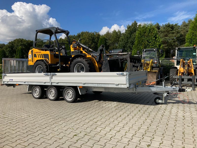 Ein gelber Traktor steht auf der Rückseite eines Anhängers.