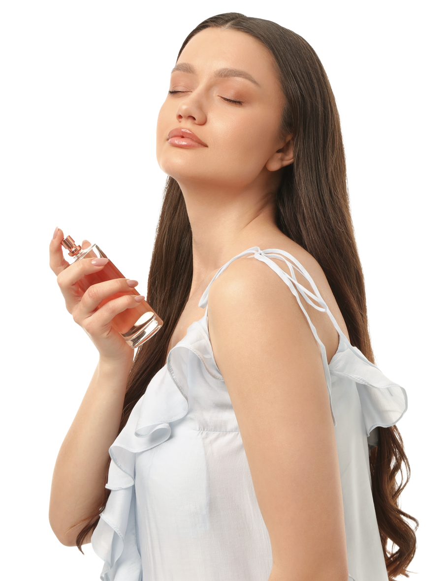 Femme vaporisant du parfum sur son cou, les yeux fermés, vêtue d'une robe bleu clair.