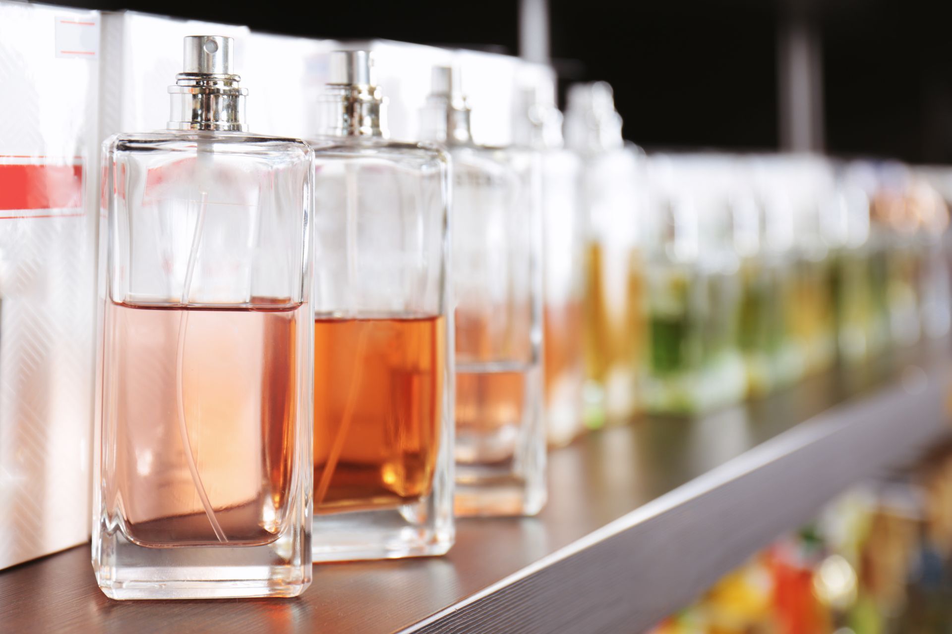 Flacons de parfum de différentes couleurs sur une étagère, dans un magasin.