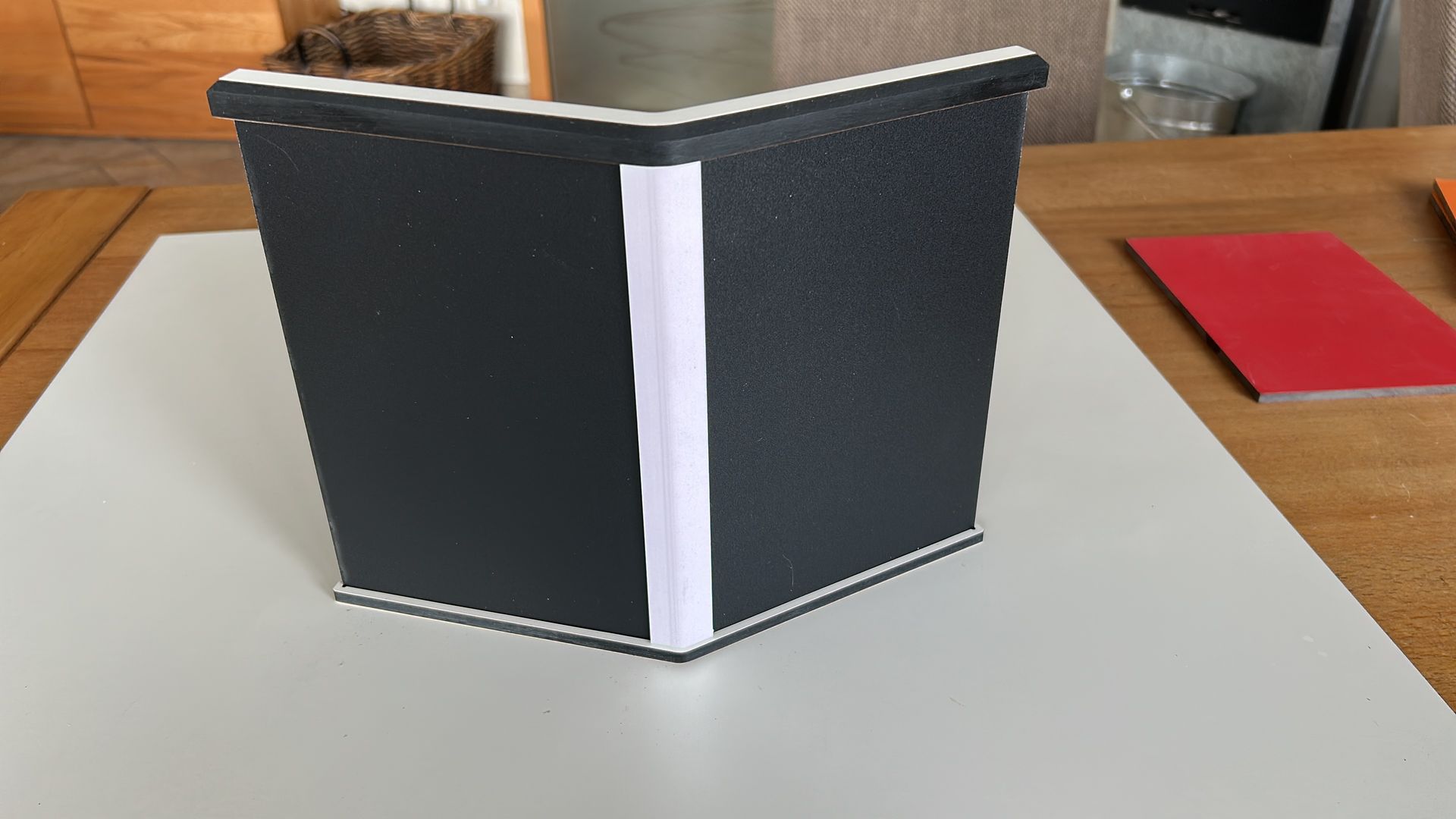 Ein schwarzes Buch liegt auf einem weißen Tisch