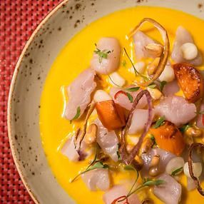 Ceviche peruano en salsa amarilla, servido en plato de cerámica, con pescado, camote y maíz.