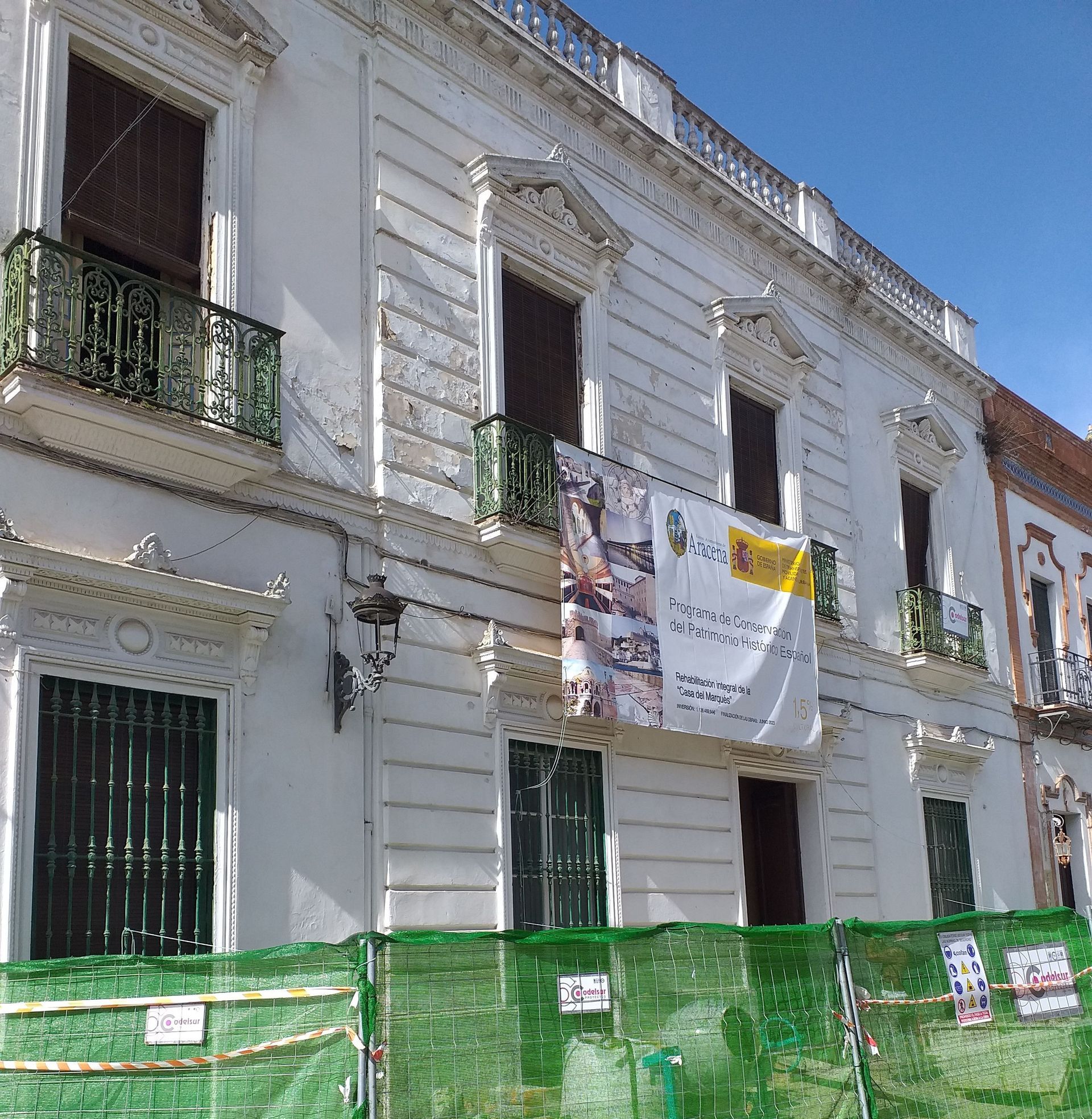 Un edificio blanco con una valla verde a su alrededor.