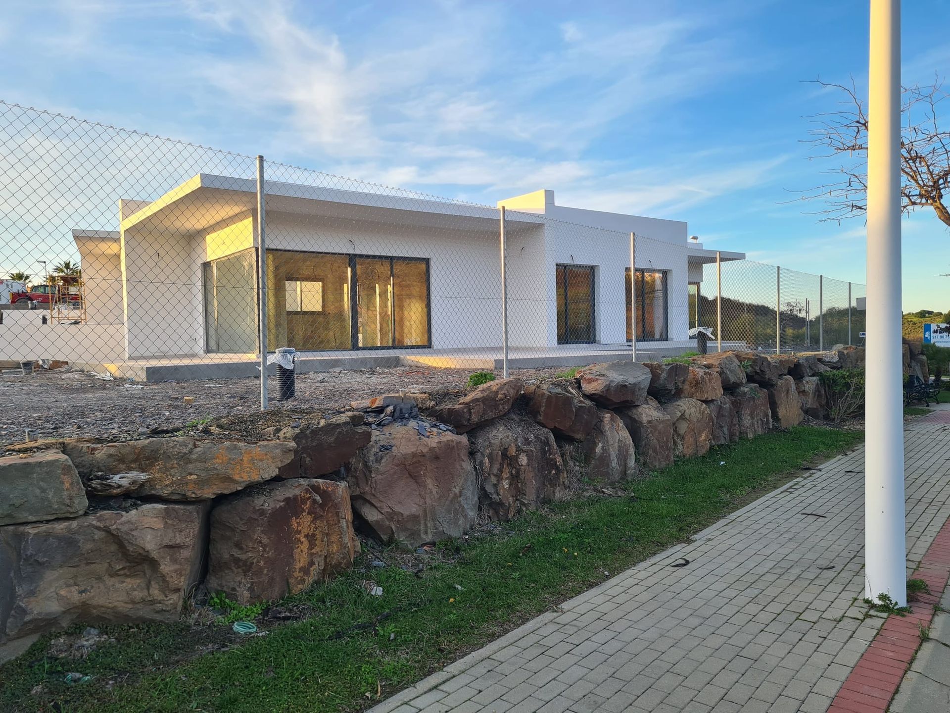Una casa blanca está rodeada por una valla de alambre y rocas.