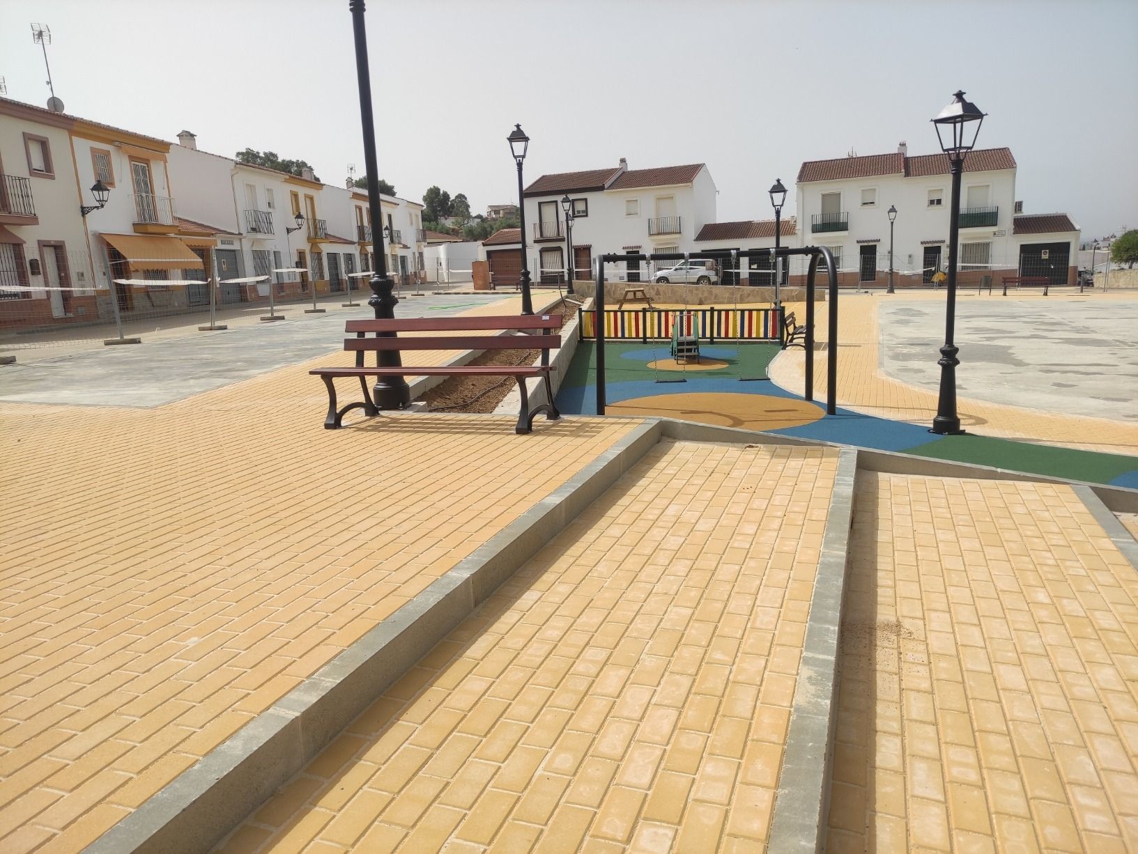 Un parque con un banco y un parque infantil al fondo.