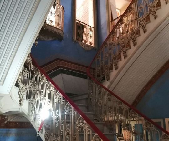 Una escalera con una barandilla roja y una pared azul.