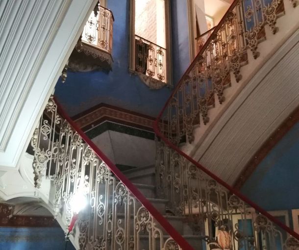 Una escalera con una barandilla roja y una pared azul.