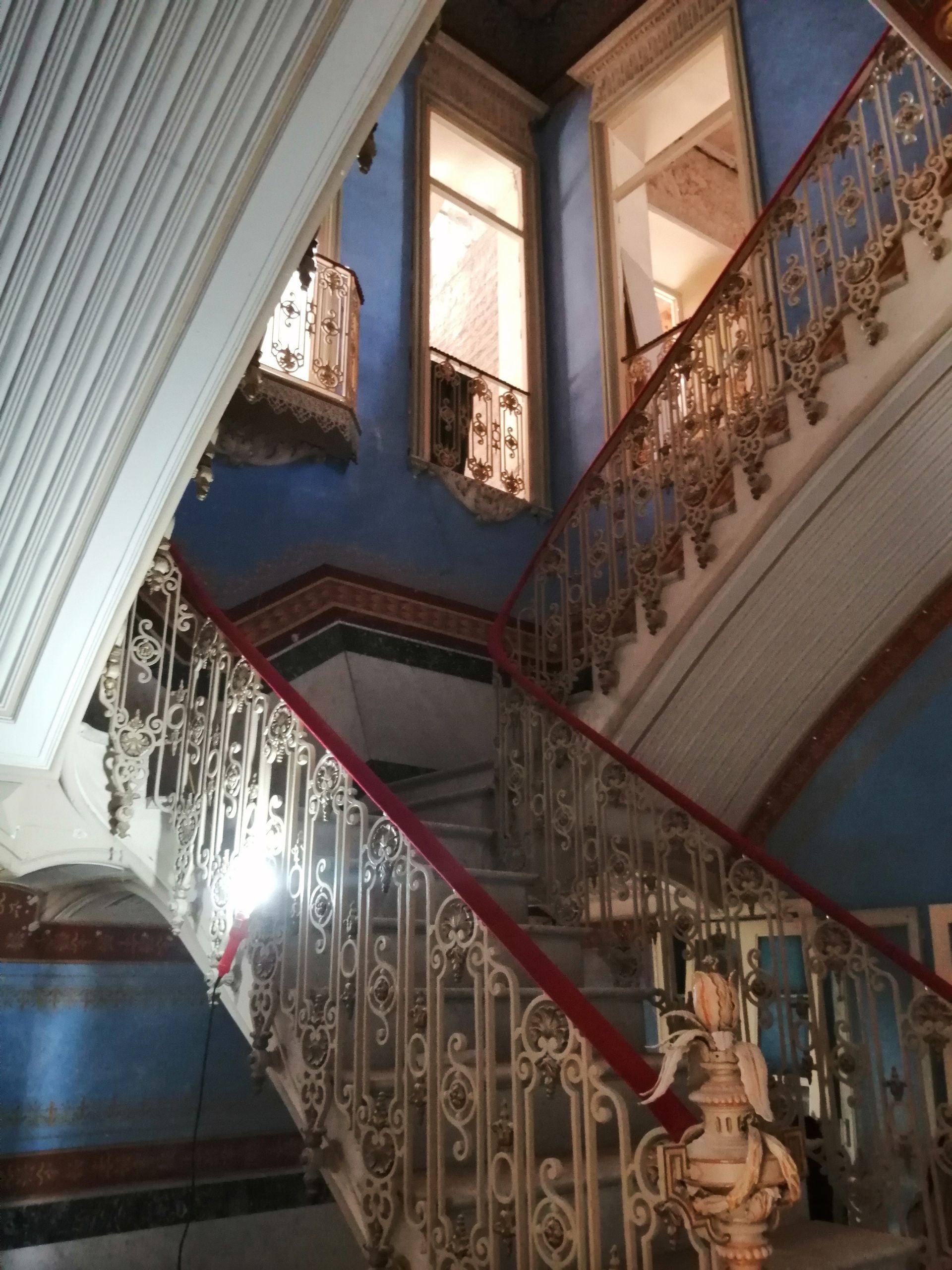 Una escalera con una barandilla roja y una pared azul.