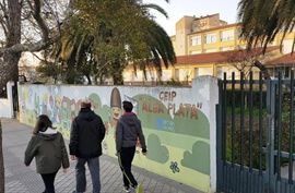 Un grupo de personas camina por una acera frente a un edificio.
