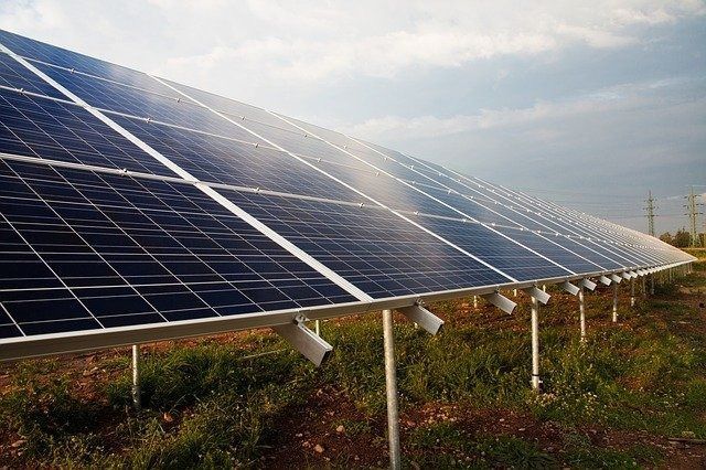 Una fila de paneles solares en un campo con un cielo azul de fondo.