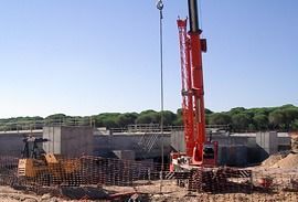 Una gran grúa roja se encuentra en lo alto de un sitio de construcción.
