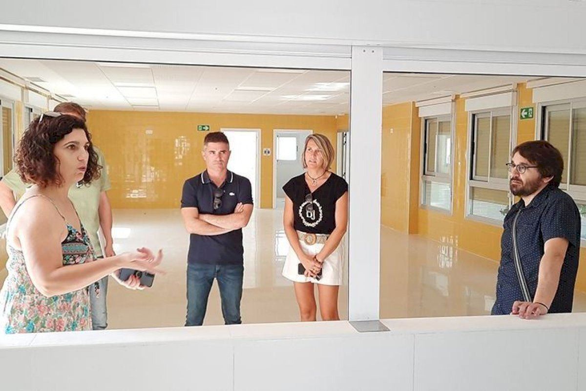 Un grupo de personas están de pie en una habitación hablando entre sí.