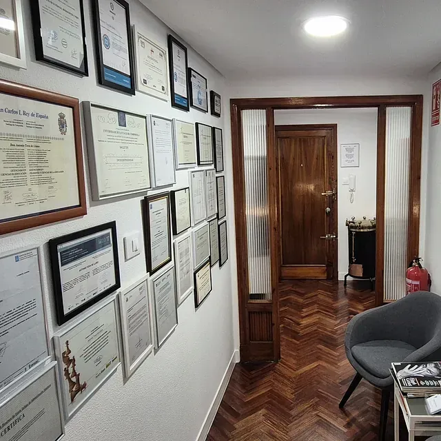 Un pasillo con muchos papeles enmarcados en la pared.