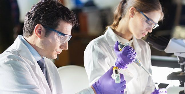 Un hombre y una mujer miran a través de un microscopio en un laboratorio.