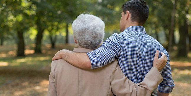 Un joven abraza a una mujer mayor en un parque.