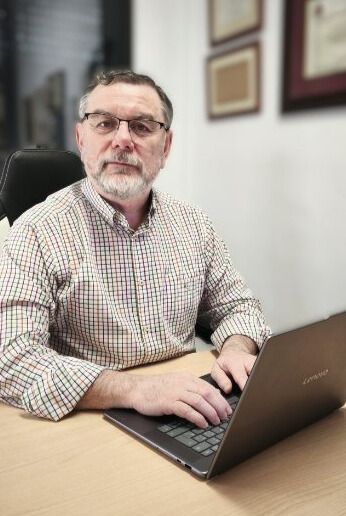 Un hombre está sentado en un escritorio utilizando una computadora portátil.