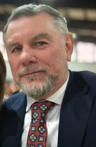 Un hombre con barba lleva traje y corbata.