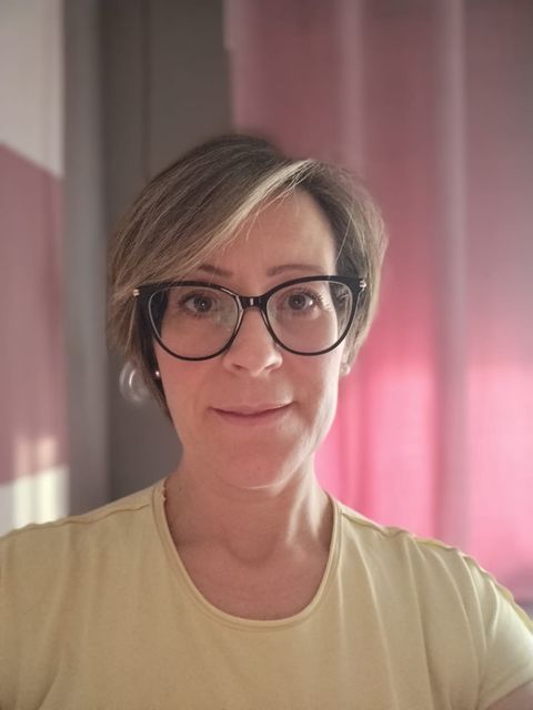 Una mujer que lleva gafas y una camiseta amarilla se está tomando un selfie.