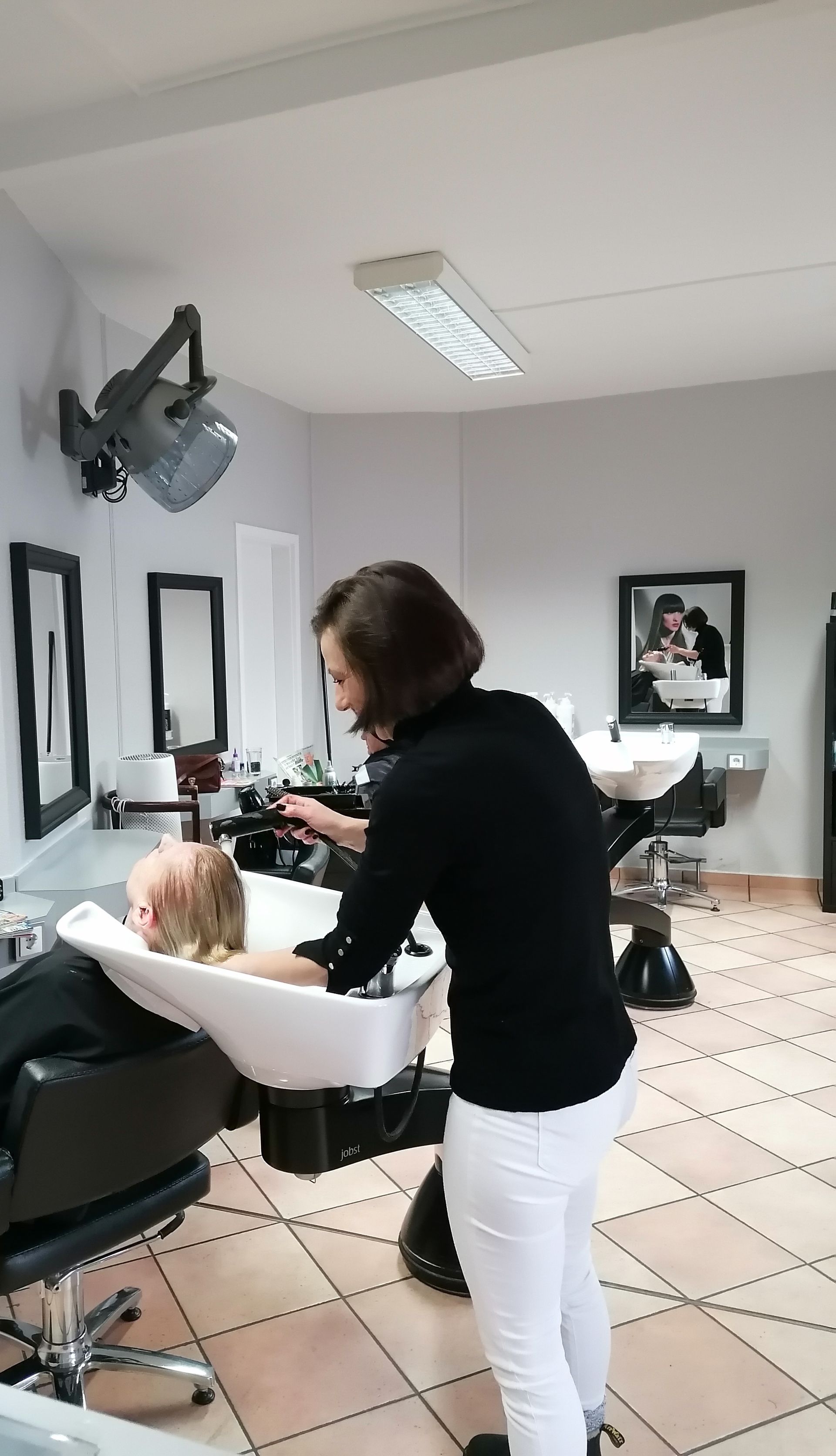 Eine Frau wäscht einem Mann in einem Salon die Haare.