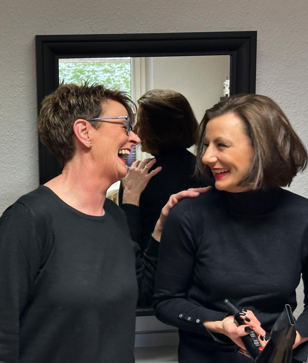 Zwei Frauen lachen vor einem Spiegel