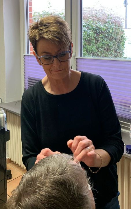 Eine Frau schneidet einem Mann in einem Salon die Haare.