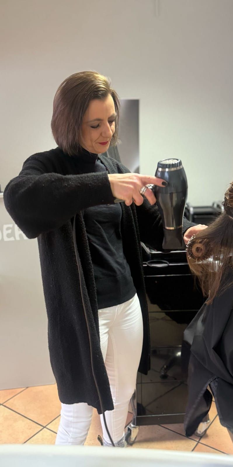 Eine Frau föhnt in einem Salon die Haare einer anderen Frau.