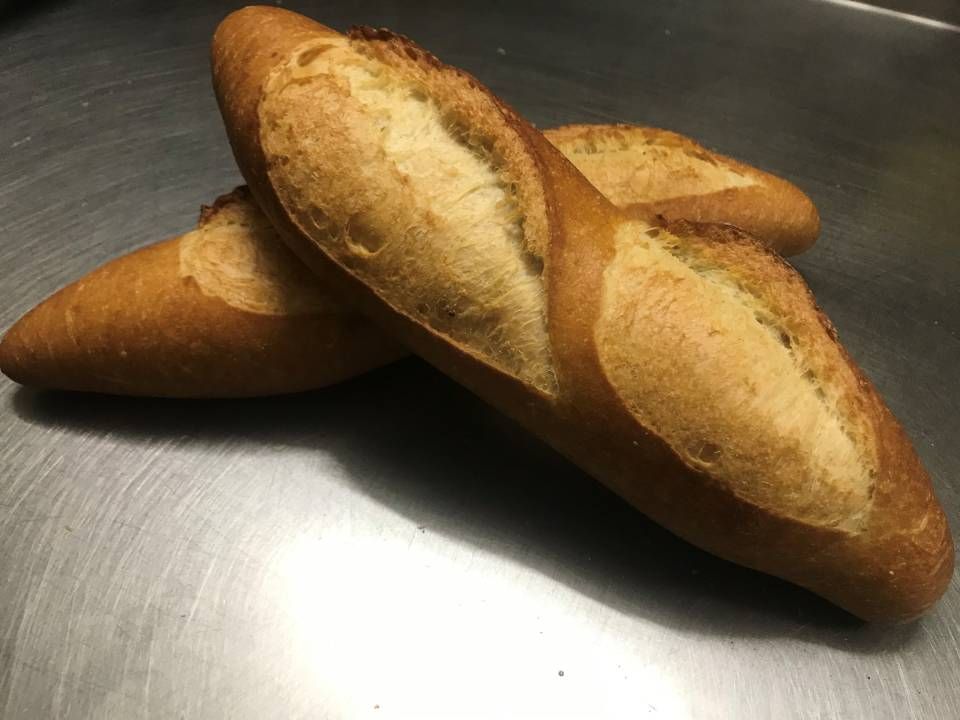 Pagnotta di pane croccante e oblungo, spolverata di farina bianca.