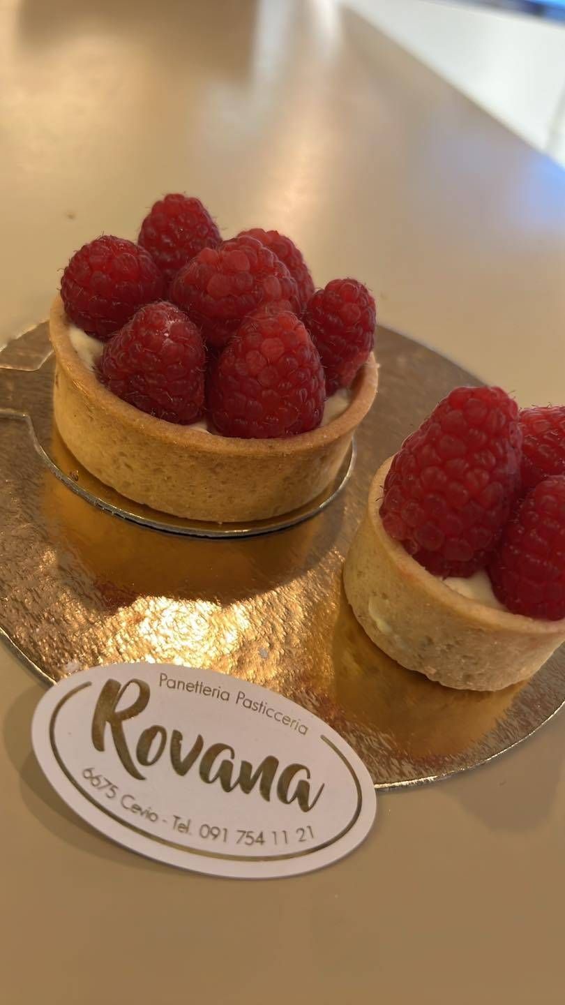 Due crostatine ai lamponi su carta dorata, accanto a un'etichetta con la scritta 