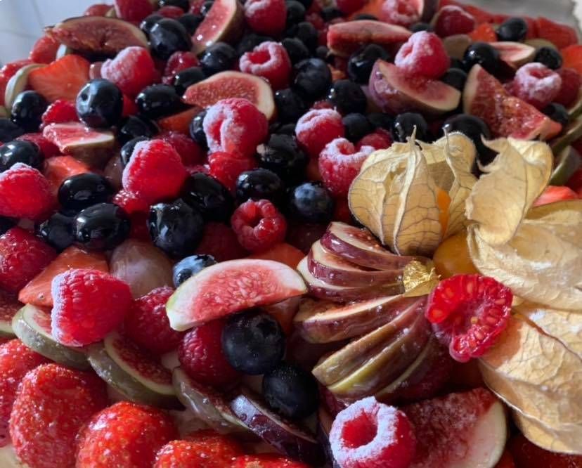 Primo piano di una crostata di frutta con fragole, mirtilli, lamponi e fichi a fette.