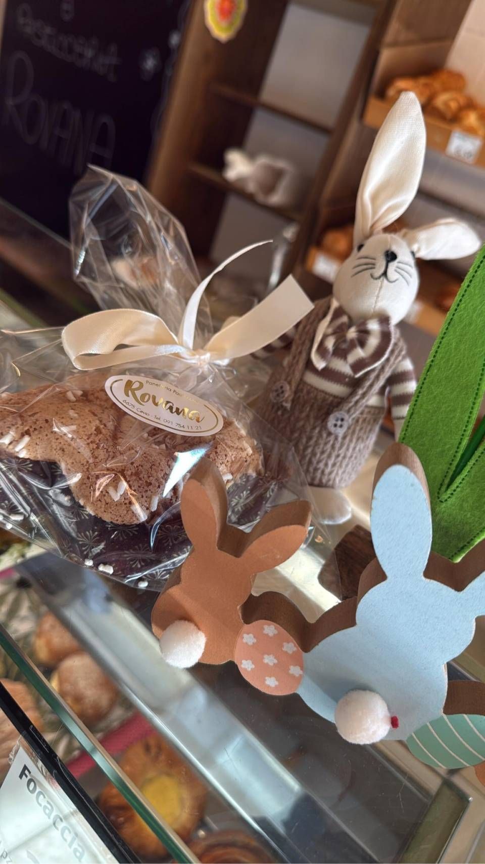 Esposizione pasquale in una panetteria: coniglietto di peluche con dolcetti e coniglietti decorativi in ​​legno.