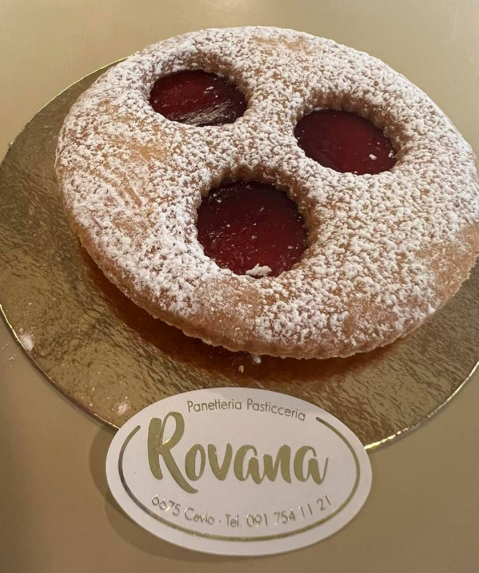 Crostate di frutta con frutti di bosco e pesche assortiti, esposte su un vassoio in un ambiente da pasticceria.