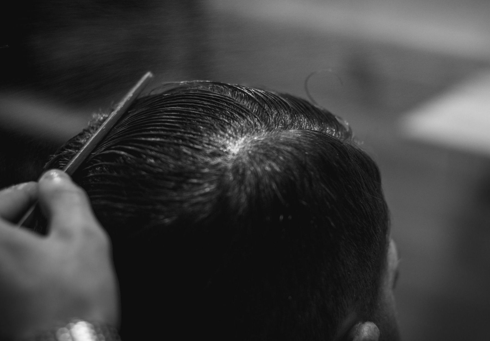 Una persona está peinando el cabello de un hombre en una fotografía en blanco y negro.