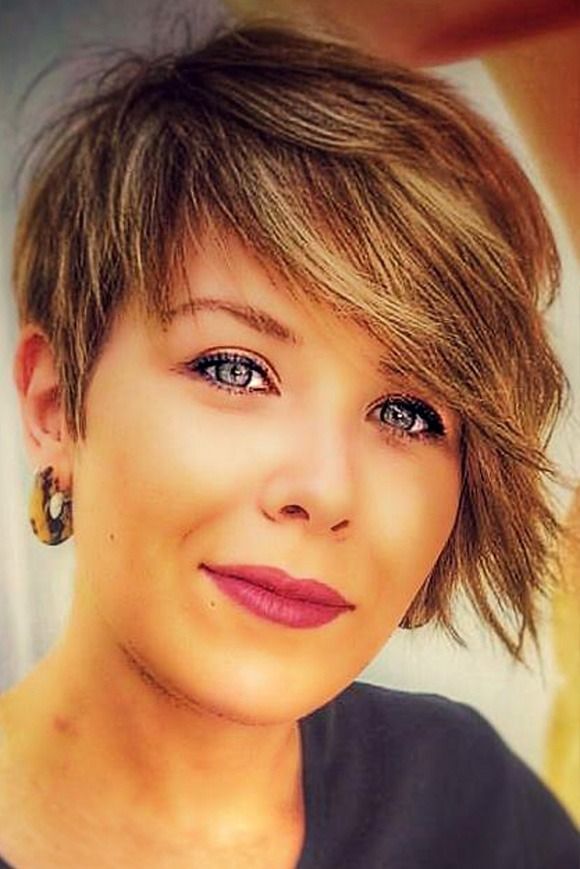 Un primer plano del rostro de una mujer con cabello corto y pendientes.