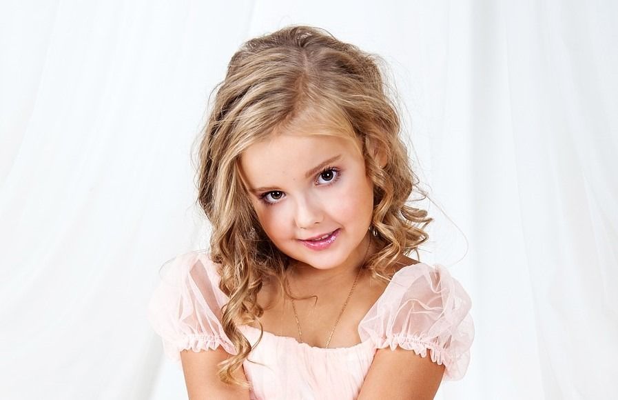 Una niña con un vestido rosa está mirando a la cámara.