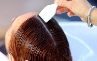 Una mujer se está tiñendo el pelo en la peluquería.