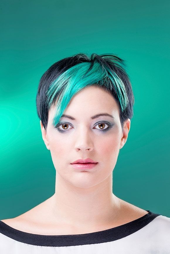 Una mujer con cabello corto azul lleva una camisa de rayas blancas y negras.