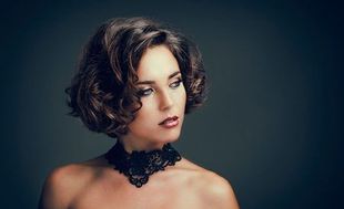 Una mujer con cabello rizado lleva un collar gargantilla de encaje negro.