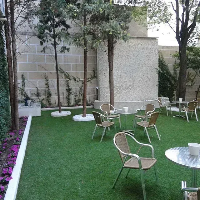 Un césped con sillas y mesas frente a un edificio.