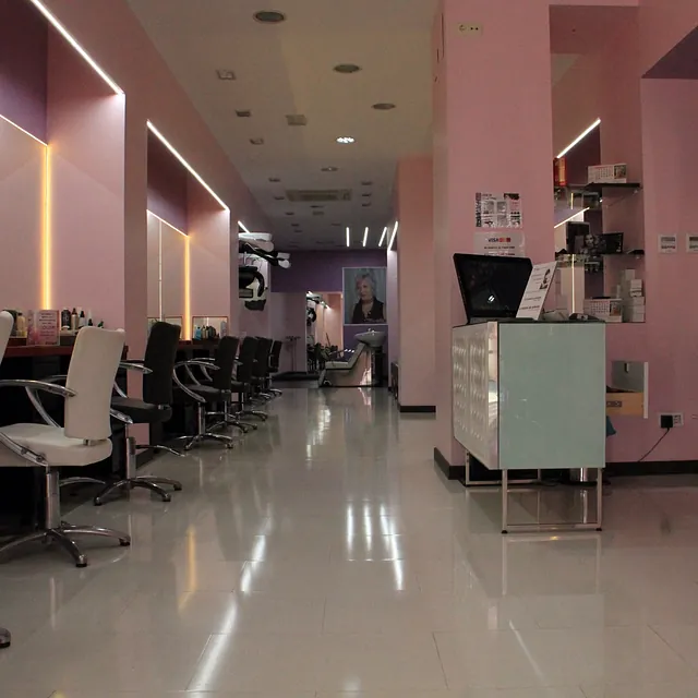 Una peluquería con paredes rosas y sillas blancas.