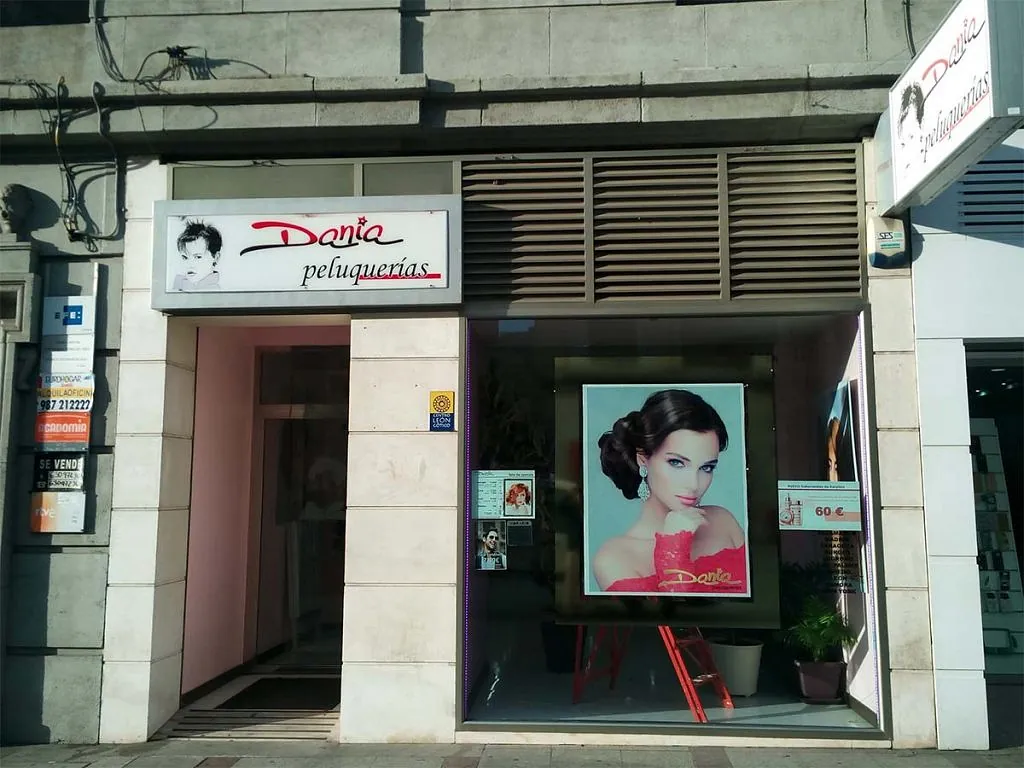 El frente de una peluquería con una foto de una mujer en la ventana.