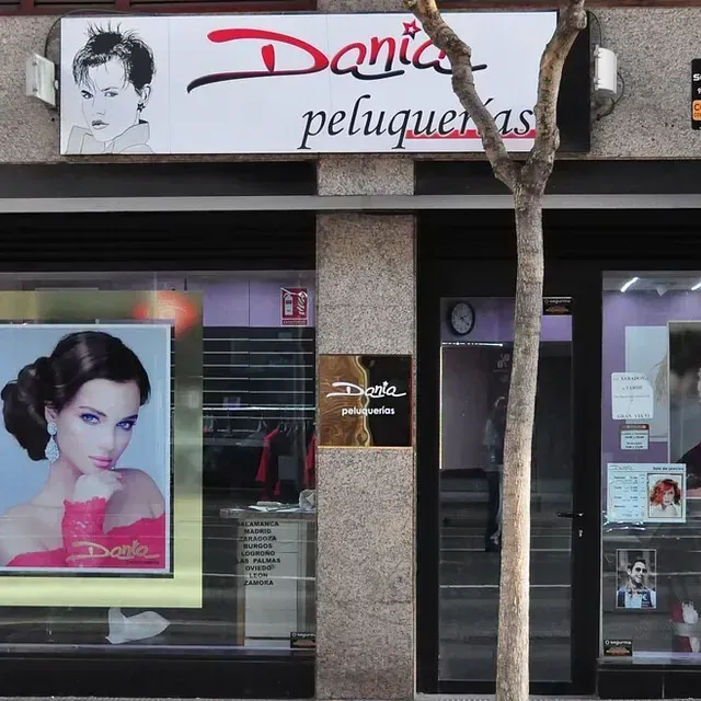 Un escaparate con un cartel que dice 'dania peluqueria'