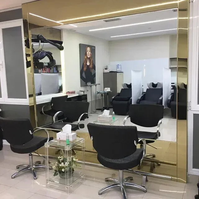 Un salón con sillas negras y un espejo grande.