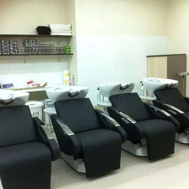 Una fila de sillas negras en un salón con lavabos.