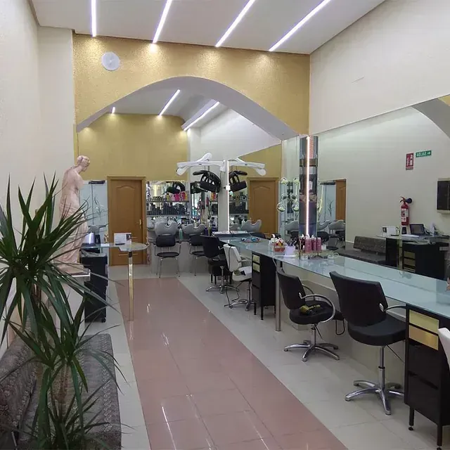 Un largo pasillo en una peluquería con sillas y mesas.