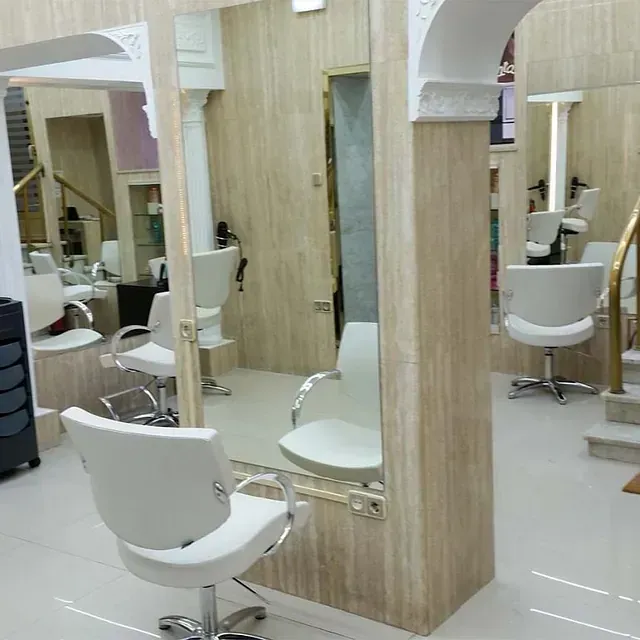 Una peluquería con sillas blancas y espejos.