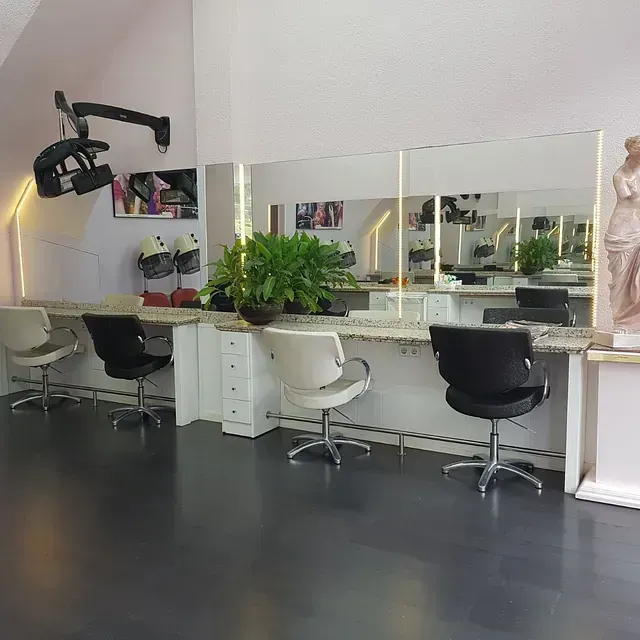 Una peluquería con sillas, mesas, espejos y una estatua.