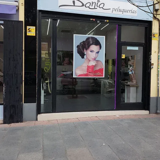 Una foto de una mujer con un vestido rojo cuelga en el escaparate de una peluquería Dania.